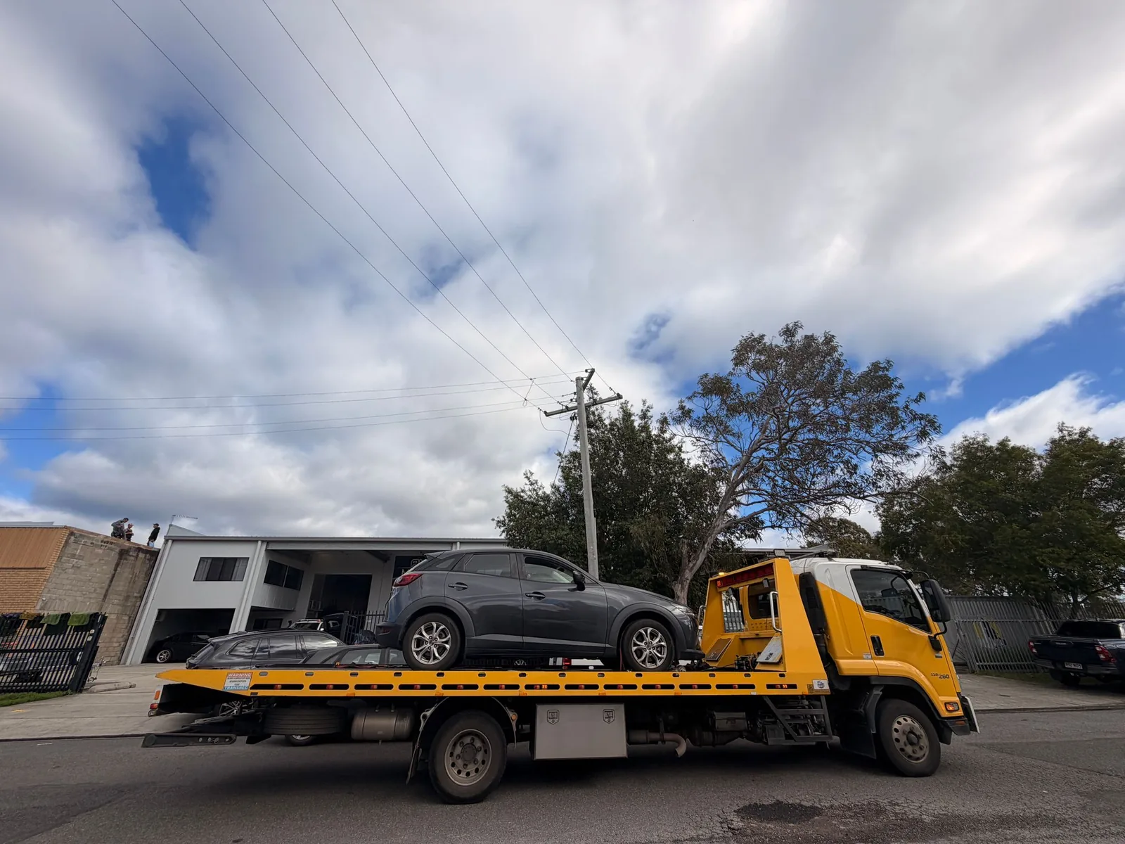 TowFast Brisbane yellow tilt tray tow truck carrying a grey SUV in Brisbane